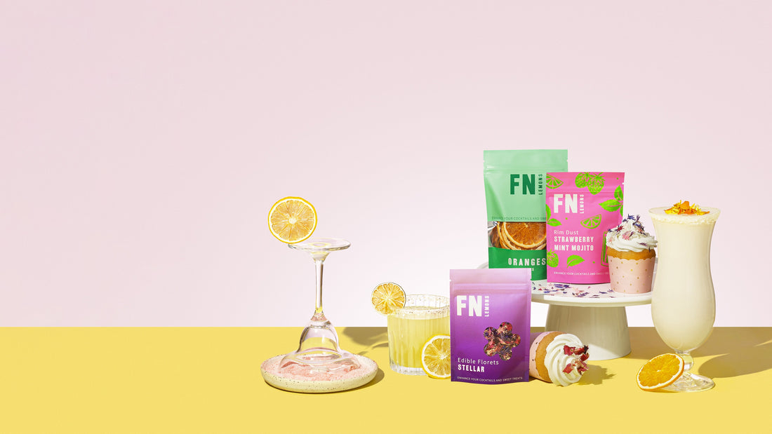 F N Lemons garnish pouches with finished cocktails on a pink and yellow backdrop