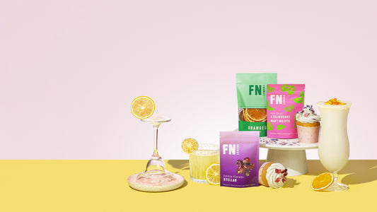 F N Lemons garnish pouches with finished cocktails on a pink and yellow backdrop