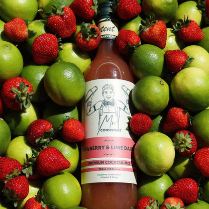 Bottle of 'Consistent' Strawberry & Lime Daiquiri mix surrounded by strawberries and limes.