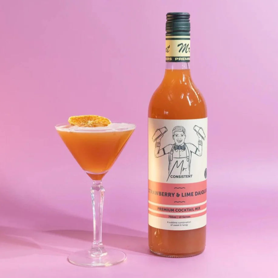 Bottle of strawberry and lime cocktail mix with a cocktail on a pink background